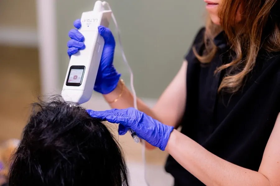 Lyndsay performing hair regeneration therapy with a specialized device