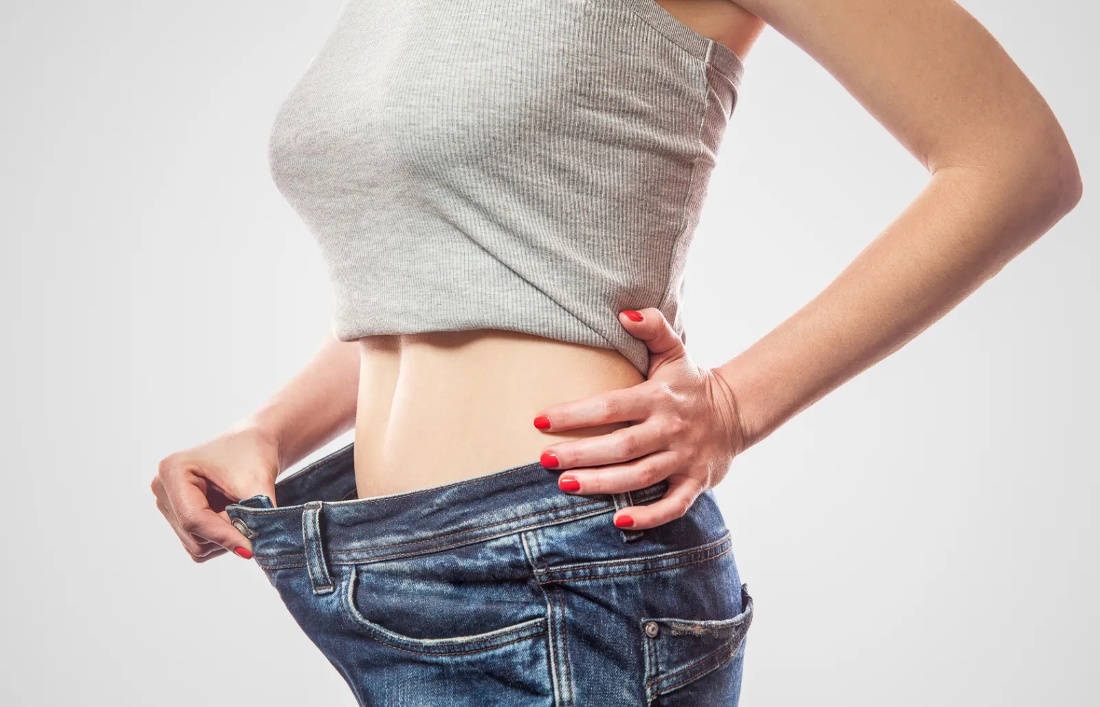 Woman showing off weight loss results in loose-fitting jeans