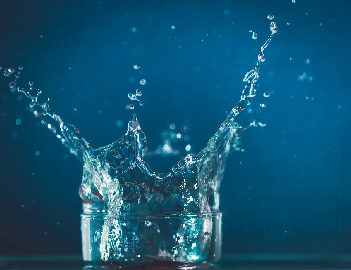 Water splashing in a clear glass, representing hydration and wellness